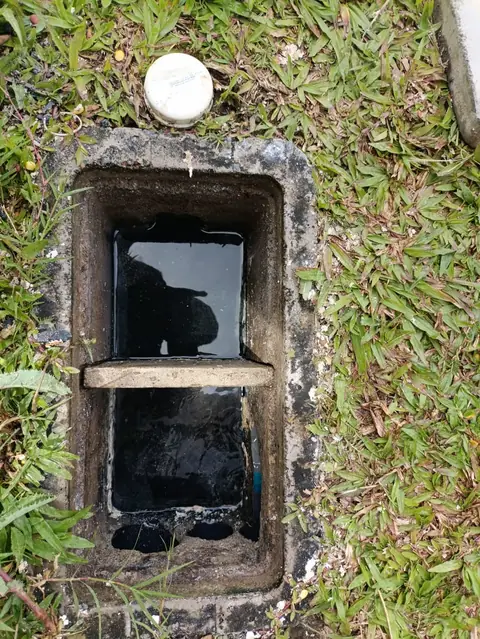Caja de registro de concreto abierta en un jardín